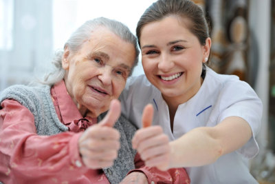 female caregiver and elderly woman doing thumbs-up